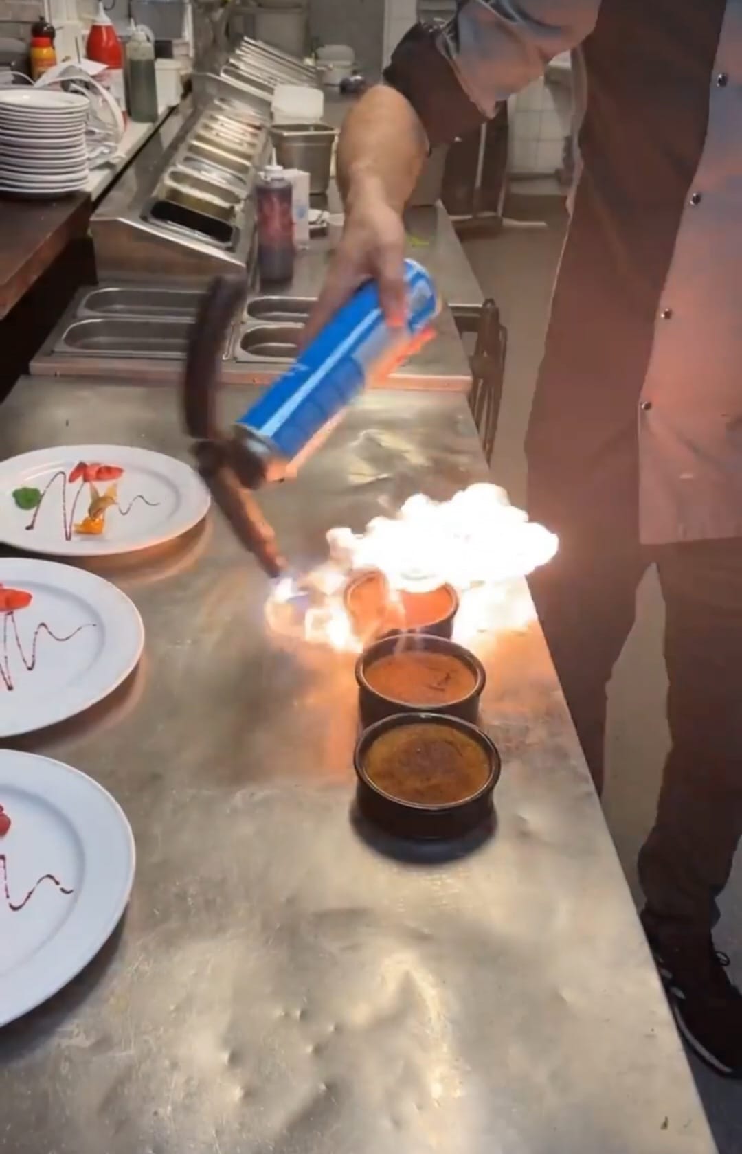 Kocken bränner crème brûlée vid det öppna köket