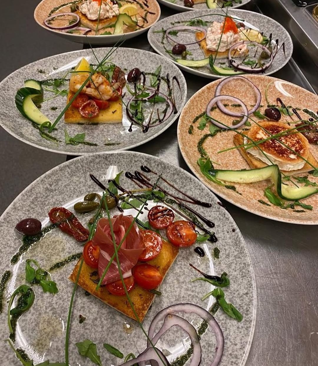Förrätter med parmaskinka, räkor och bruschetta uppdukade i köket